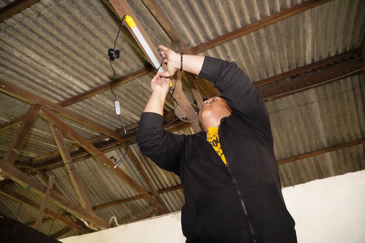 A team member fits an indoor light fitting to the ceiling of a home.