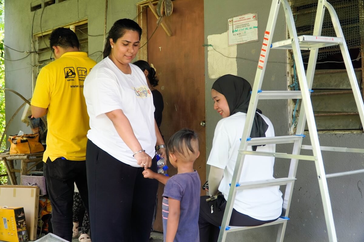 Google volunteers talking with a resident and a child at a doorway during installation work.